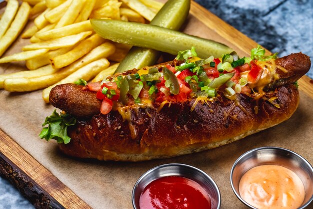 Foto gratuita vista laterale hot dog salsiccia alla griglia con pomodori verdi formaggio fuso jalapeno pepe nel panino hot dog con salsa di patatine fritte e cetriolo sottaceto su una tavola