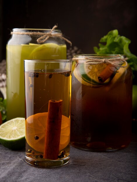 Side view iced lemon tea with cinnamon fresh apple juice and slice of lime