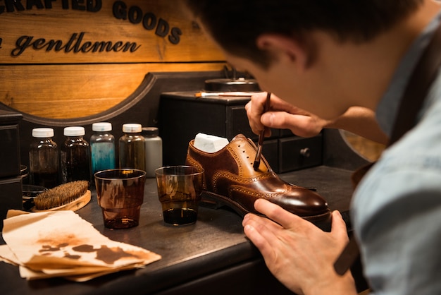 Free photo side view image of young concentrated shoemaker