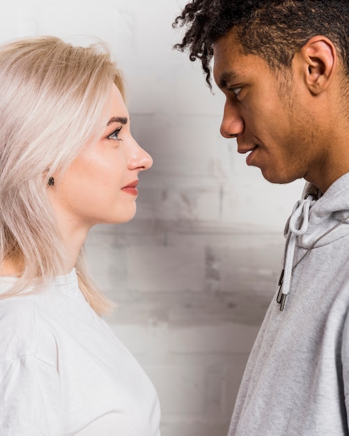 Side view of a interracial couple's friend looking at each other