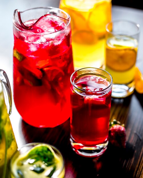 テーブルの上のレモンとイチゴのスライスとさまざまな清涼飲料を活性化する側面図