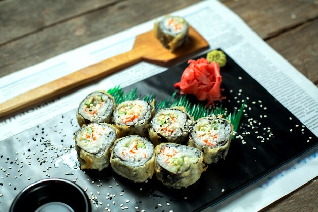 日本の伝統的な食べ物の天ぷら寿司マキの側面図は、ブラックボードに生姜と醤油を添えてください。