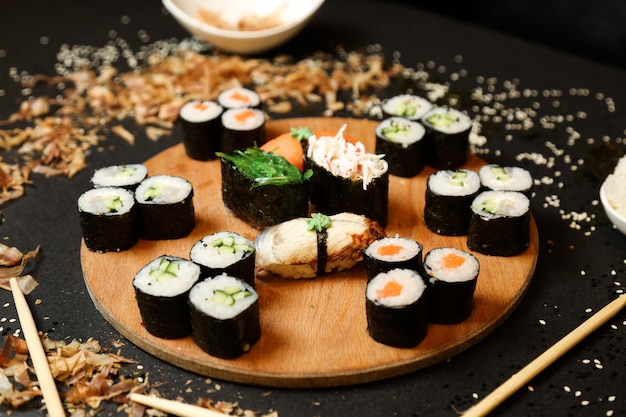 Side view kappa maki rolls with shake maki and sashimi sushi with chopsticks on a stand