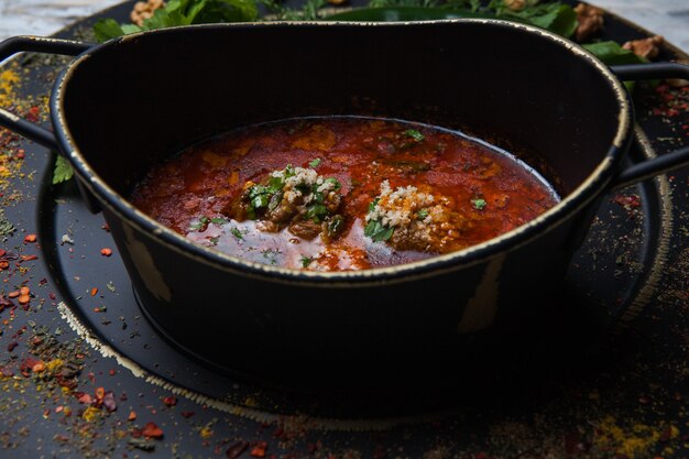 Side view kharcho with spice and greens in dark plate