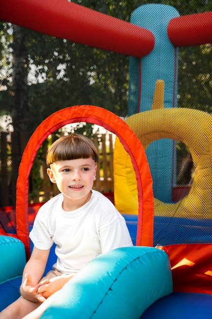 Side view kid having fun in bounce house