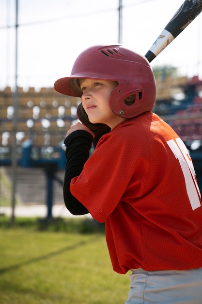 Foto gratuita ragazzo di vista laterale che tiene la mazza da baseball