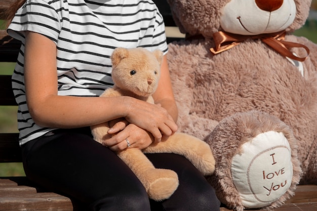 Free photo side view kid holding teddy bear outdoors