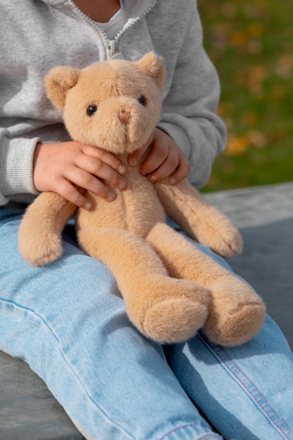 Free photo side view kid holding teddy bear outdoors