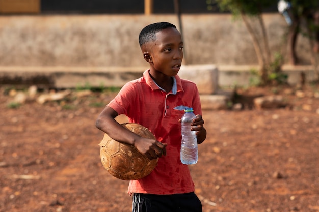 Foto gratuita bambino di vista laterale che tiene una bottiglia d'acqua