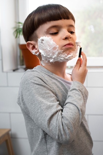 Side view kid learning how to shave