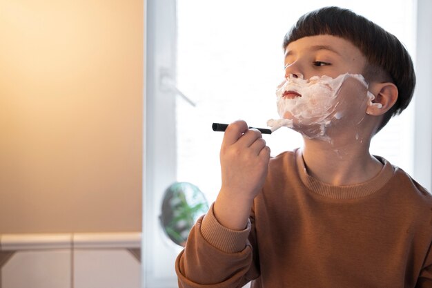 剃る方法を学ぶ側面図の子供