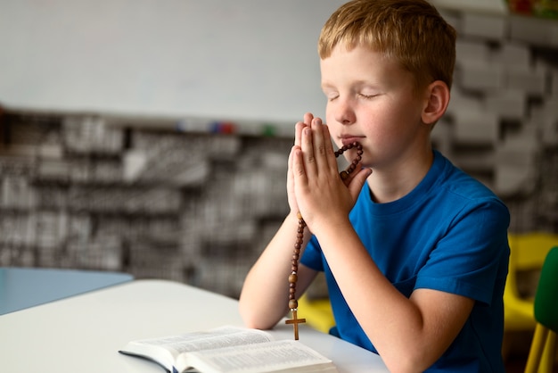 Free photo side view kid praying at sunday school