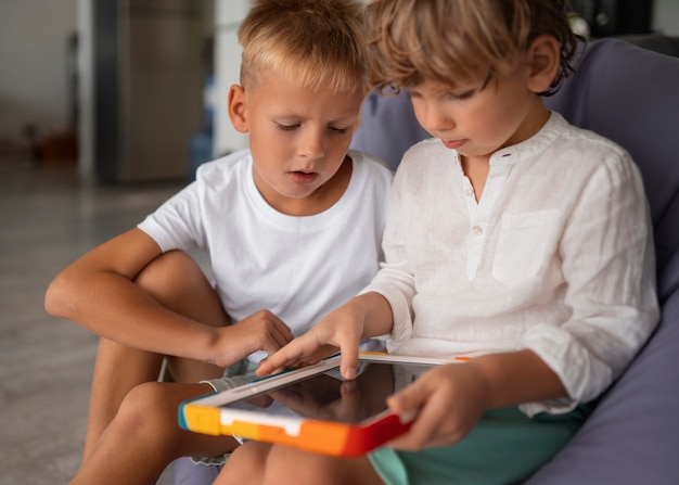 Free photo side view kids playing with tablet