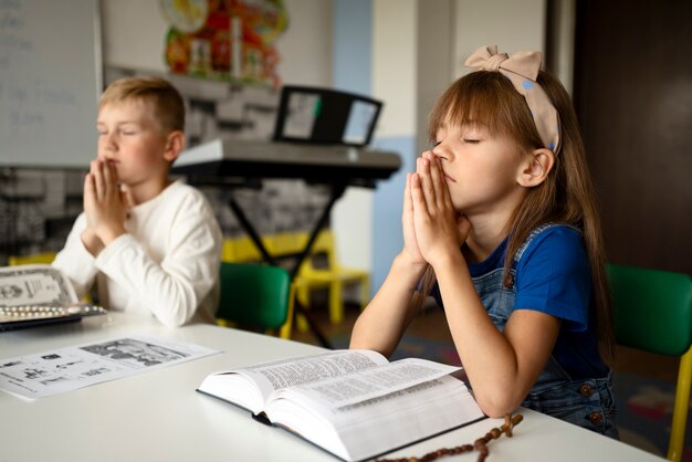 日曜学校で祈るサイドビューの子供たち