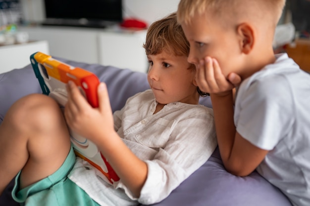 Side view kids with tablet indoors