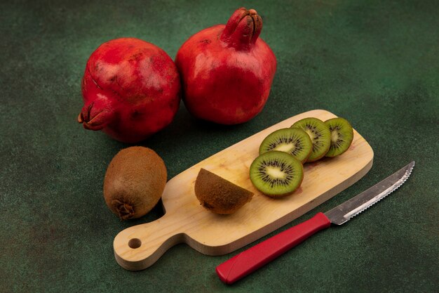 녹색 벽에 칼과 석류 커팅 보드에 측면보기 키위 조각