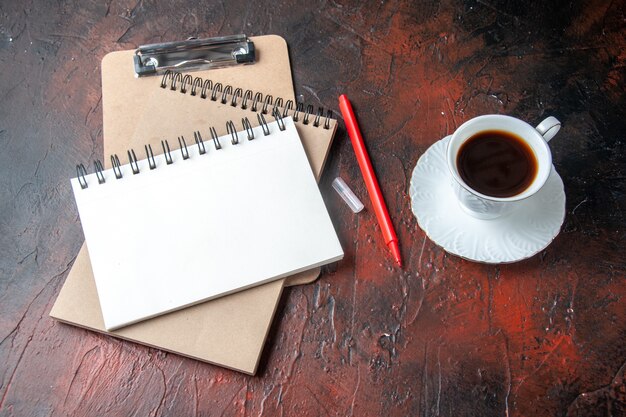 Вид сбоку спиральных блокнотов из крафт-бумаги с ручкой и чашкой чая на темном фоне