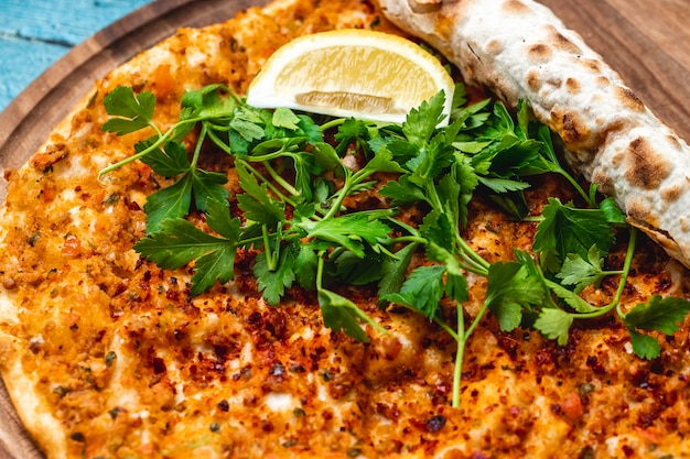 Foto gratuita vista laterale lahmacun con carne macinata cipolla pomodoro aglio verdi e fetta di limone