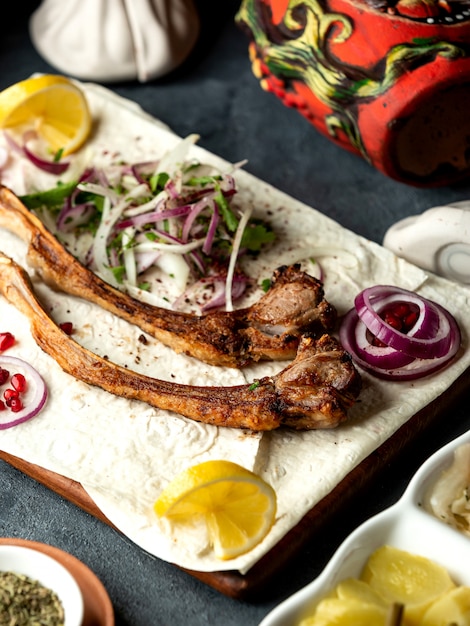 Side view of lamb ribs kebab with herbs and onion on lavash