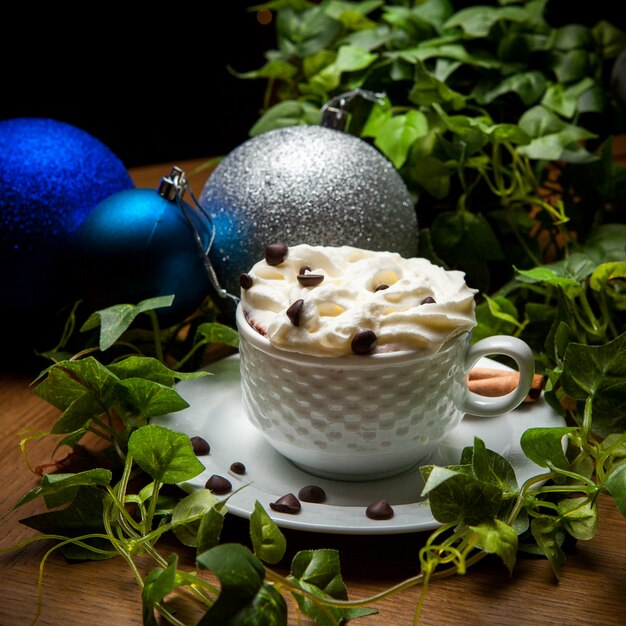 Side view latte with coffee beans and grape branch and christmas ball in cup