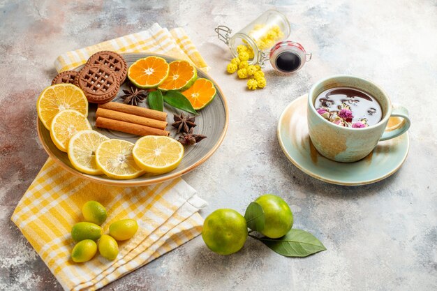 Side view of lemon slices cinnamon lime on a wooden cutting board and biscuits on white table