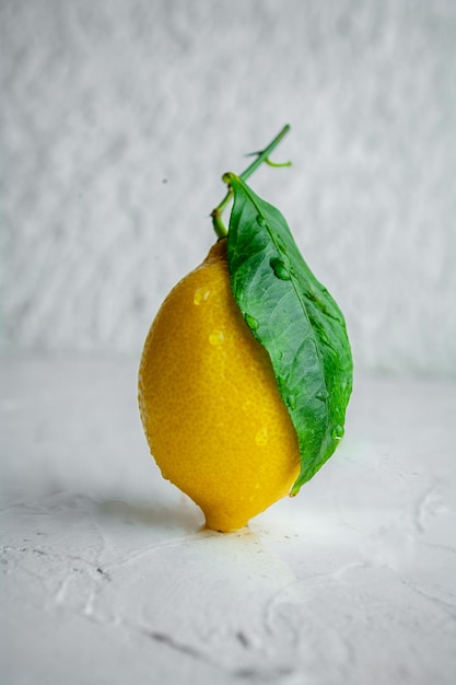 Side view lemon with leaves on white textured background. vertical