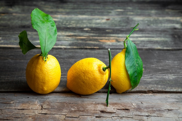 Free photo side view lemons with leaves on dark wooden background. horizontal