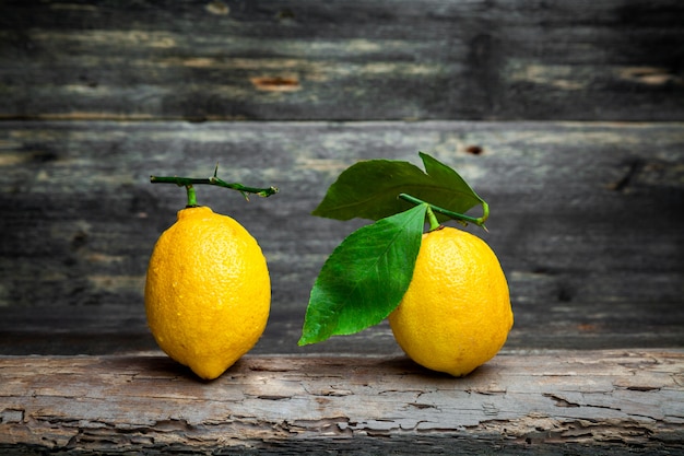 Side view lemons with and without leaves on dark wooden background. horizontal