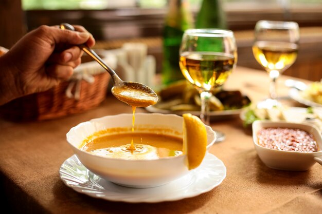 Вид сбоку суп из чечевицы Мерси в миску и руку с ложкой над миской