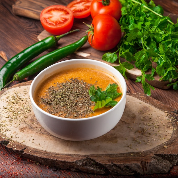 Side view lentil soup with green pepper and tomato and parsley in white plate