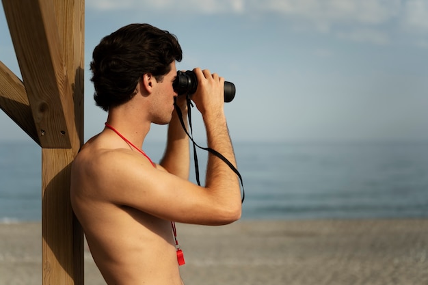 Foto gratuita bagnino di vista laterale con il binocolo