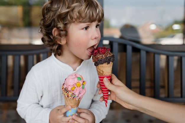 Ragazzino di vista laterale che lecca il cono gelato