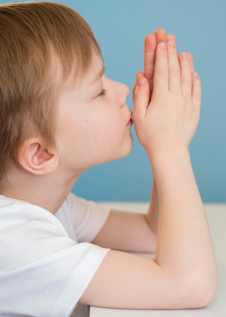 Side view of little boy praying