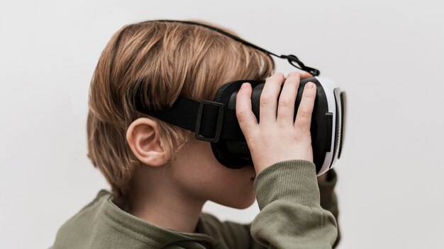 Маленький мальчик, использующий гарнитуру виртуальной реальности, вид сбоку