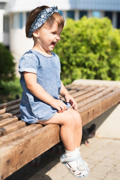 Free photo side view of little girl on bench