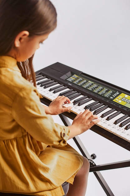 전자 키보드를 연주하는 방법을 배우는 어린 소녀의 모습