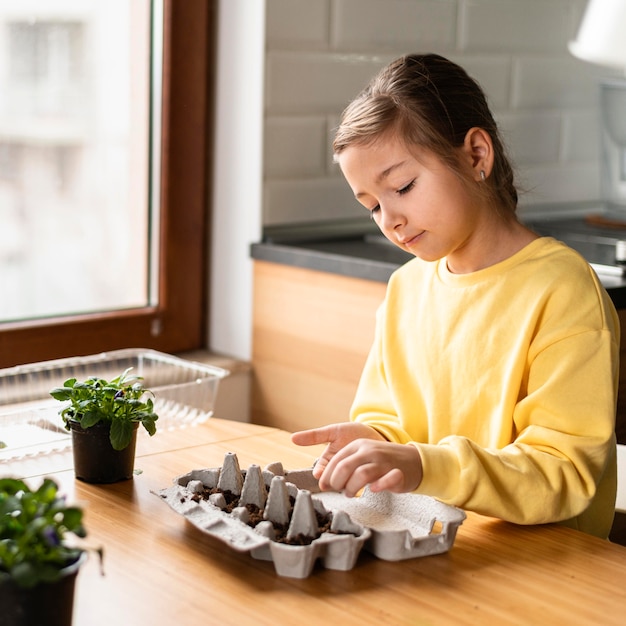 Side view of little girl planting seeds at home