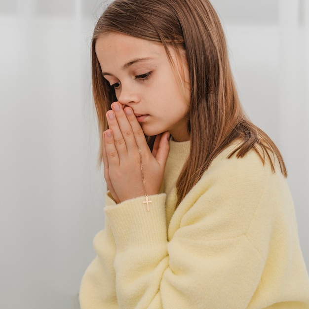 Free photo side view of little girl praying at home