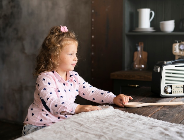 Free photo side view little girl sitting in the kitchen