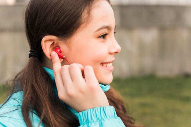 Side view little girl in sportswear listening to music