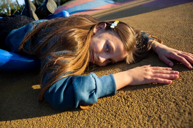 Side view little girl staying on the edge of a slide