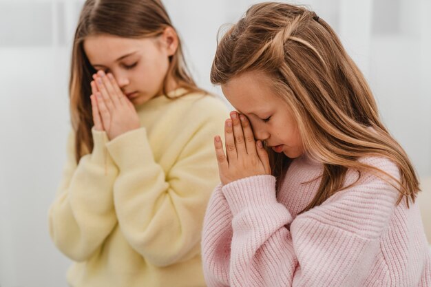 Маленькие девочки молятся дома, вид сбоку