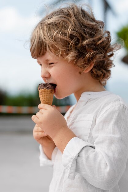 Side view little kid eating ice cream