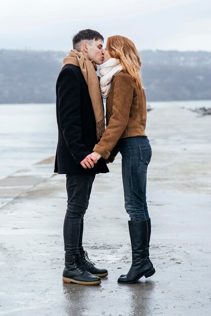 Side view of loving couple by the lake during winter