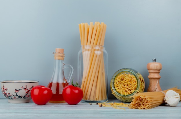 Side view of macaronis as bucatini spaghetti vermicelli with tomato garlic butter on wooden surface and blue background