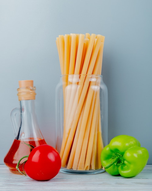 Foto gratuita vista laterale dei maccheroni come bucatini con pepe e burro di pomodoro su superficie di legno e parete blu