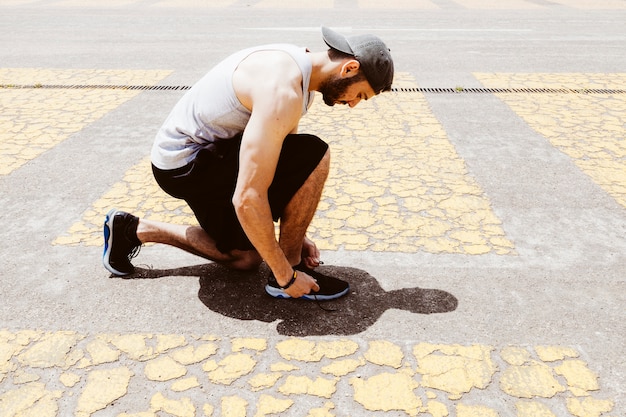 Free photo side view of a male athlete tying shoelace