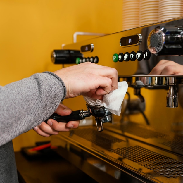 Side view of male barista cleaning professional coffee machine