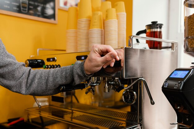 Side view of male barista in the coffee shop next to coffee grinder