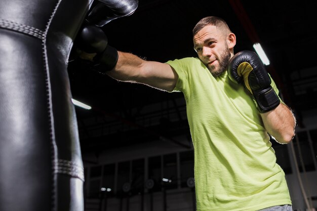 Vista laterale del pugile maschio che si esercita con il sacco da boxe